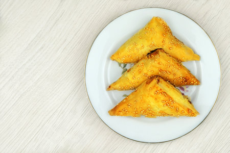 Eastern cuisine. Samosas in a plate on a wood background. Home cooking. Fast food.