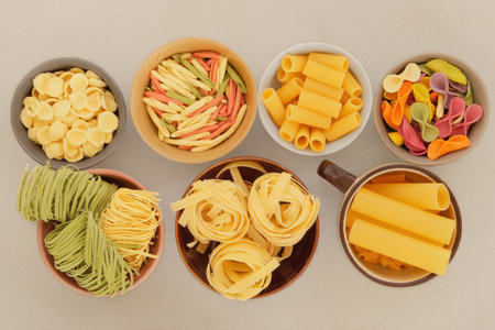 Top view. Varieties of multi-colored pasta. Set of uncooked pasta in bowls on a light background. Storing different types of dry pasta at home.の写真素材