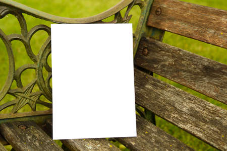 A blank white card template sitting on a wooden and iron bench in the summerの写真素材