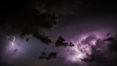 Lightning Bolt Discharges in Purple Storm Clouds at Nightの写真素材