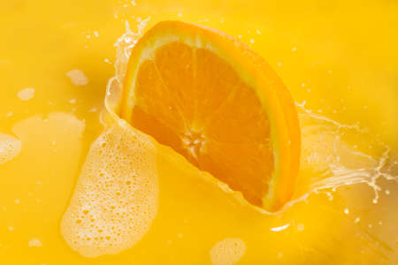 Orange Slices Splashing into Orange Juice on White Backgroundの写真素材