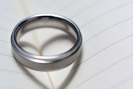Wedding Ring Band on Book with Heart Shadow Close Upの写真素材