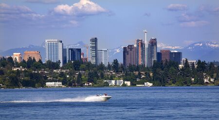 City of Bellevue from Lake Washington with Speed Boat and Snow Capped Mountains in Background\r\rResubmit--In response to comments from reviewer have further processed image to reduce noise, sharpen focus and adjust lighting.の写真素材