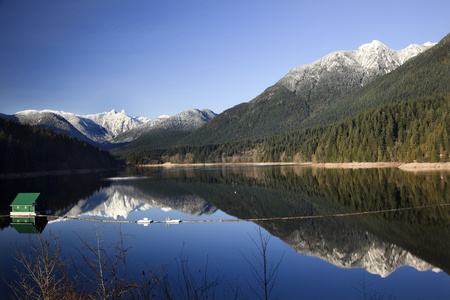 Capilano Reservoir Lake Long Reflection Green Building Dam Snowy Two Lions Snow Mountains Vancouver British Columbia Pacific Northwestの写真素材