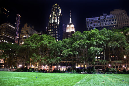 Bryant Park New York City Green Grass Skyline Apartment Buildings Empire State Building Nightのeditorial素材