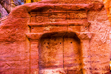 Tomb Outer Siq Canyon Petra Jordan Petra Jordan.  Colorful Yellow Pink Canyon becomes rose red when sun goes.  The rose red can become blood red.  Reds are created by magnesium in sandstone.の写真素材