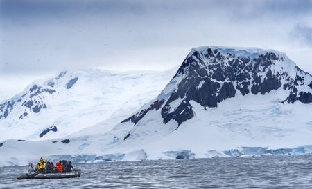 Tourist Rubber Boats Snowng Glaciers Snow Mountans Charlotte Bay Antarctic Peninsula Antarctica.  Glacier ice blue because air squeezed out of snow.の写真素材