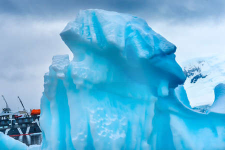 Snowing Red Kayaks Iceberg Blue Glacier Paradise Harbor Bay Antarctic Peninsula Antarctica.  Glacier ice blue because air squeezed out of snow.の写真素材