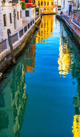 Colorful small canal and bridge creates beautiful reflections in Venice Italyの写真素材