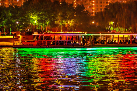Colorful Tourist Boat Night Illuminated Bridge Hai River Water Reflection Tianjin China. Hai River has beautiful lights at night creative colorful reflections.の写真素材