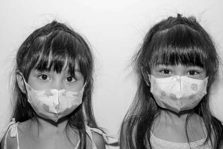 Asian female twins wearing a mask to protect against the Corona virus that can spread through the...