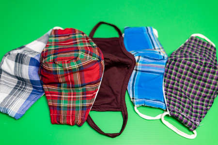 Different colors of washable face masks on green background. Fashionable face masks reusable and...