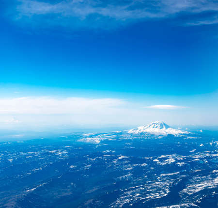 Aerial View of Idaho mountains from the sky while inside an airplane. View of brown mountains and trees covered with snowの写真素材