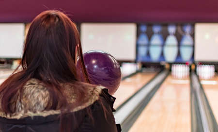 A bowling ball while being aimed to the target by a female adult in a bowling tournament. Purple  bowling ball and blurry bowling alley backgroundの写真素材