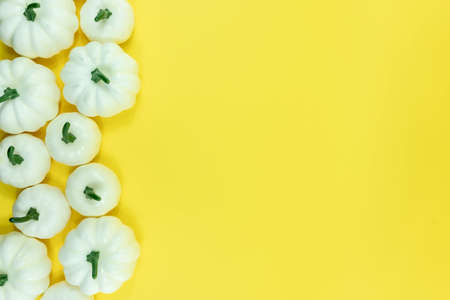 Autumn bottom border banner of white pumpkins, gourds and fall decor on yellow background with copy spaceの写真素材