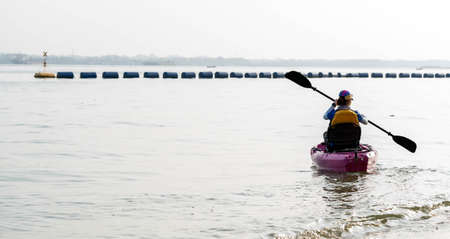 Rear view of woman paddling kayak. Paddling the canoe or small boat. Kayaking, canoeing, paddling