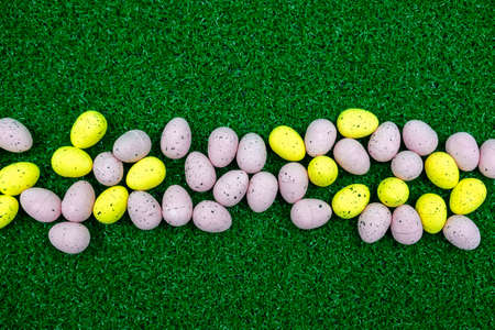 Colorful Yellow and Pink easter egg with freckle patterns on grass with copy spaceの写真素材