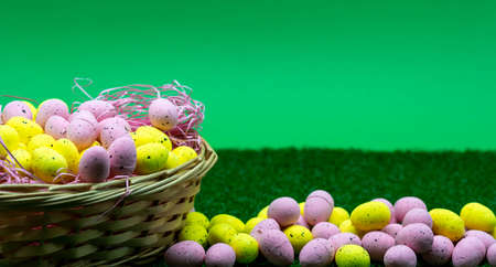 Colorful Yellow and Pink easter egg with freckle patterns in a basket with green background and...