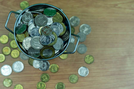 Many coins are in silver buckets on a green background. Money overflow from bucket. Coins overflow from silver bucketの写真素材