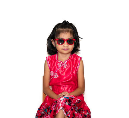 picture of beautiful liitle girl in red chinese dress wearing sun glasses sitting on chairの写真素材