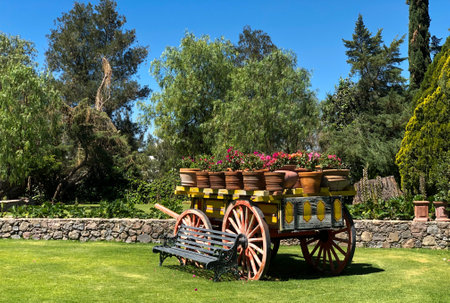 Wooden cart with pots of flowers on the green grass in the gardenの写真素材