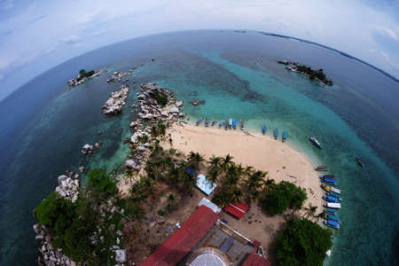 Aerial view of landscape from top lighthouse with several boats, coconut tree and coral rock surrounded turquoise water in fishbowl eyes modeの写真素材