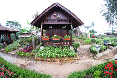 Beautiful traditional house in brown colored with two white doves as accessories on lovely flower gardenのeditorial素材
