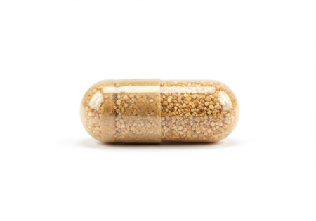 A close-up shot of a single, transparent capsule filled with small, light brown granules, isolated on a white background.の素材