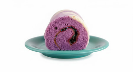 A single slice of a purple and white swirled cake roll sits on a small, teal-colored plate against a white background.の素材