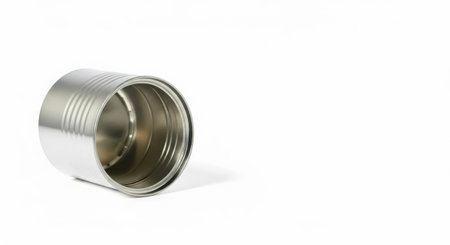 A silver metal paint can lies on its side against a stark white backdrop, showcasing its empty interior and textured exterior.の素材