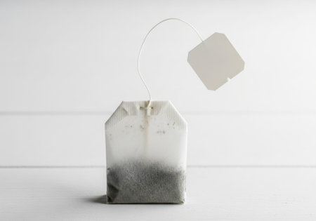 A tea bag with its tag suspended in the air, captured in motion against a clean white background.の素材