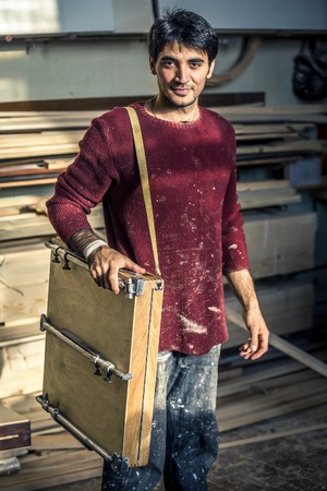 Portrait of an artist who is making this easels in his studio.