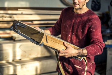 Portrait of an artist who is making this easels in his studio.