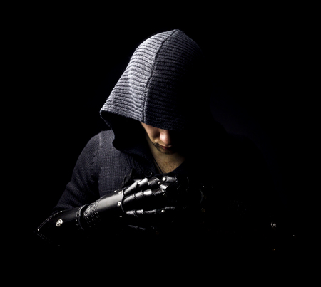 Emotional, young and attractive assassin in gloves on the black backgroundの写真素材