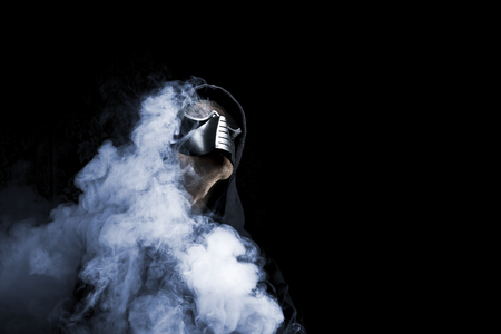 Portrait of man in mask on black background around the smoke.の写真素材