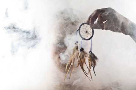 A man in abstract smoke on the black background with dreamcatcher.の写真素材