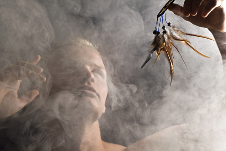 A man in abstract smoke on the black background with dreamcatcher.の写真素材