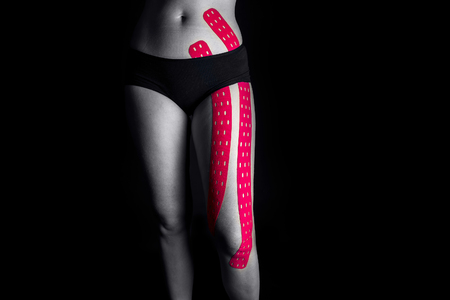 Medical taping for leg pain relief isolated on black background.