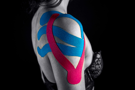 Medical taping for shoulder pain relief isolated on black background.の写真素材