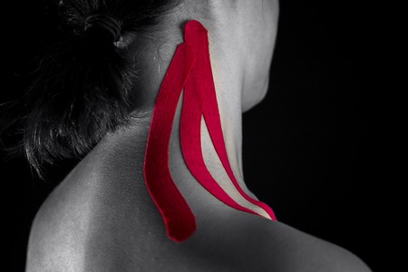 Medical taping for neck pain relief isolated on black background.の写真素材