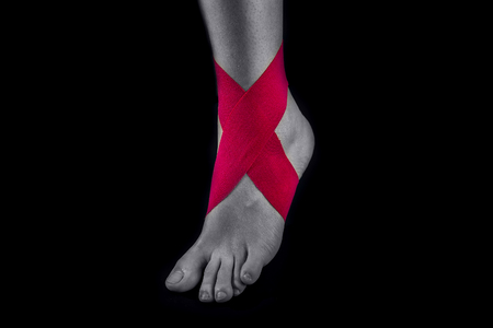 Medical taping for ankle stability isolated on black background.の写真素材