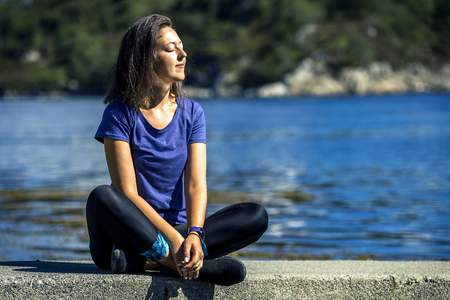 Young woman sitting on rocks and enjoy the view on fjord, Norway.の写真素材