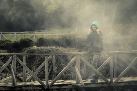 Young woman is walking by the trail near by volcano. She is observing it. You can see fog around her. Azores islands, Sao Miguel, Portugal. Furnas lake.の写真素材