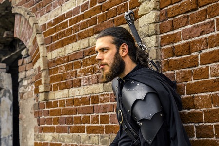 Portrait of assassin with long hair and huge beard standing next to the ruined fortress.の写真素材