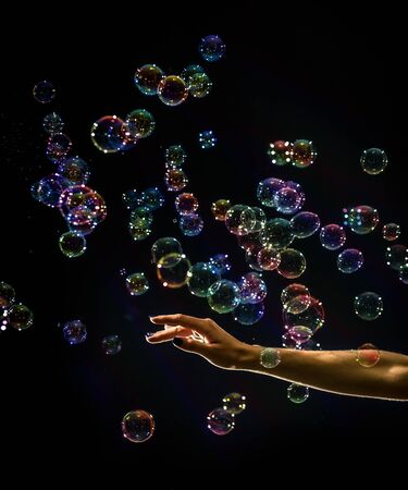 The transparent, iridescent soap bubbles isolated on black.の写真素材