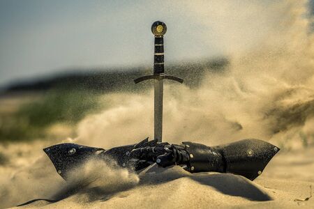 Accessories of a knight isolated on the sand during the day. Conceptual image. Sand is spreading.の写真素材