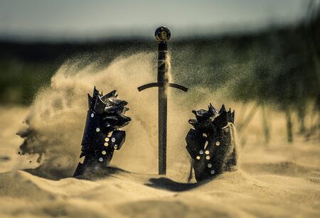 Accessories of a knight isolated on the sand during the day. Conceptual image. Sand is spreading.の写真素材