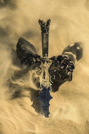 Accessories of a knight isolated on the sand during the day. Conceptual image. Sand is spreading.の写真素材