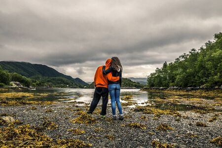 Happy couple during low water in Norway. Cloudy sky on background.