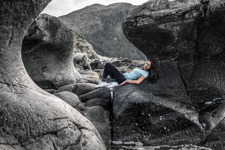 Young woman is sitting among the curve stones in Norwayの写真素材